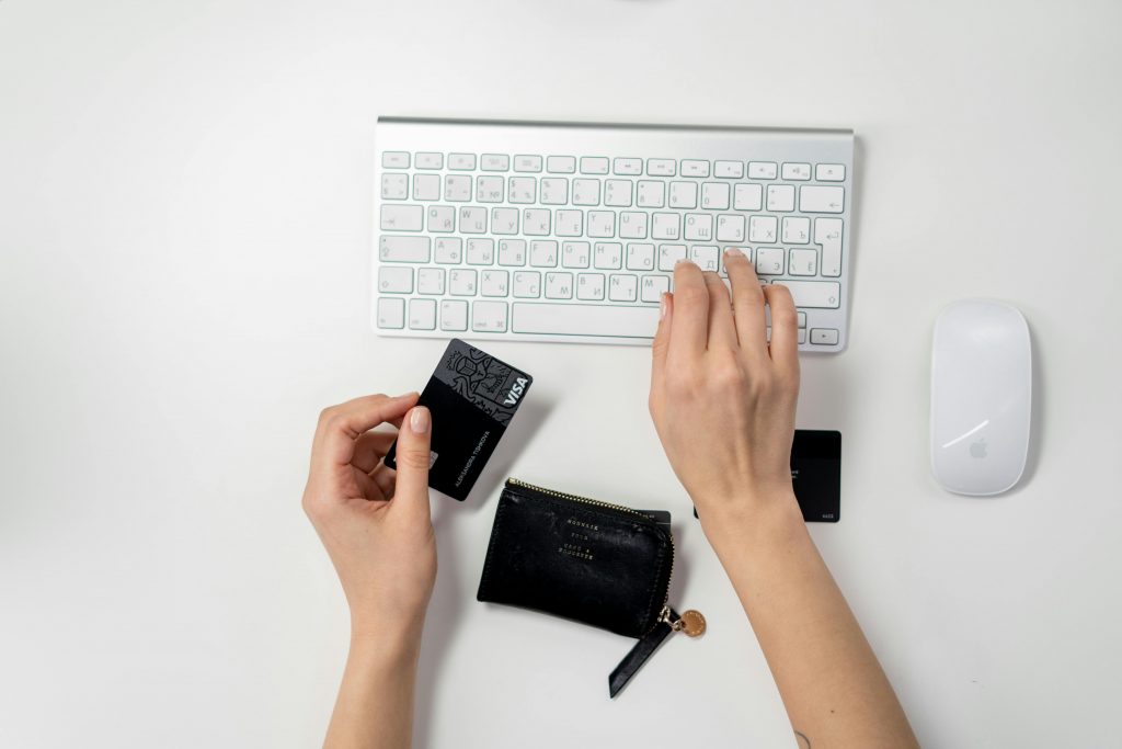 Pessoa digitando no teclado e com cartões para comprar em um e-commerce